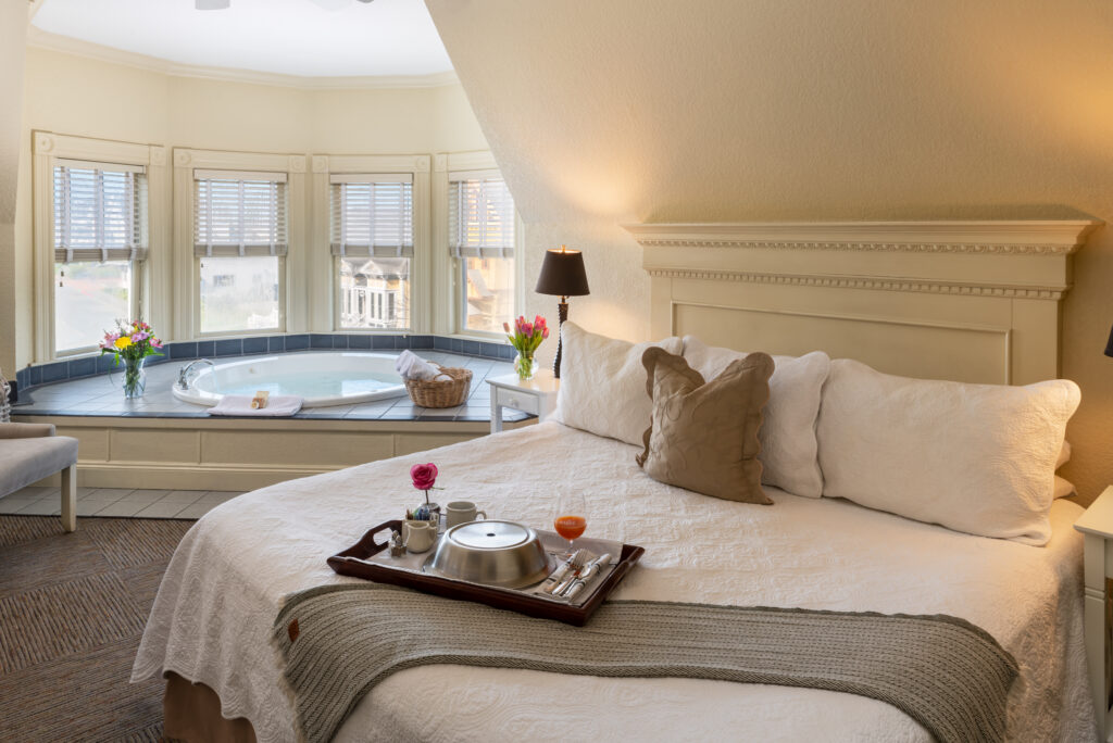 A suite at Carter House Inns, our Eureka CA Hotel with bed, breakfast tray, and soaking tub.