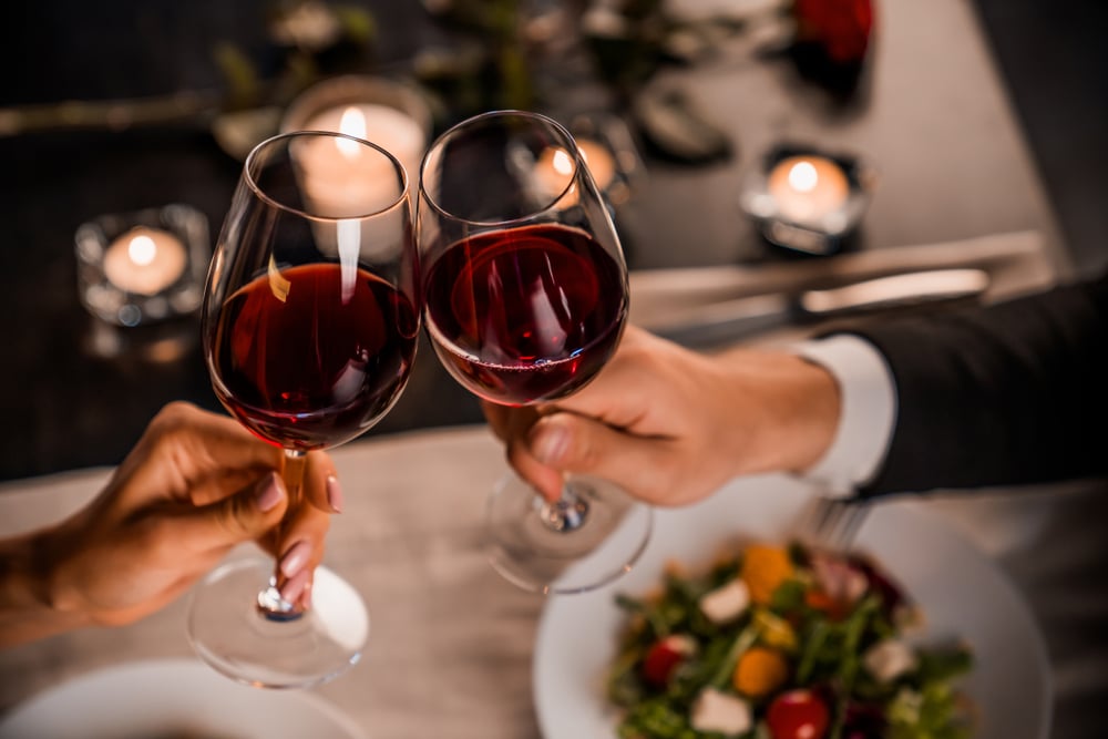 Couple toasting glasses of red wine over dinner at one of the best places to eat in Eureka CA